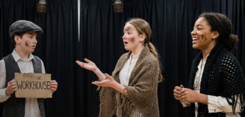 three young people in rags on stage acting